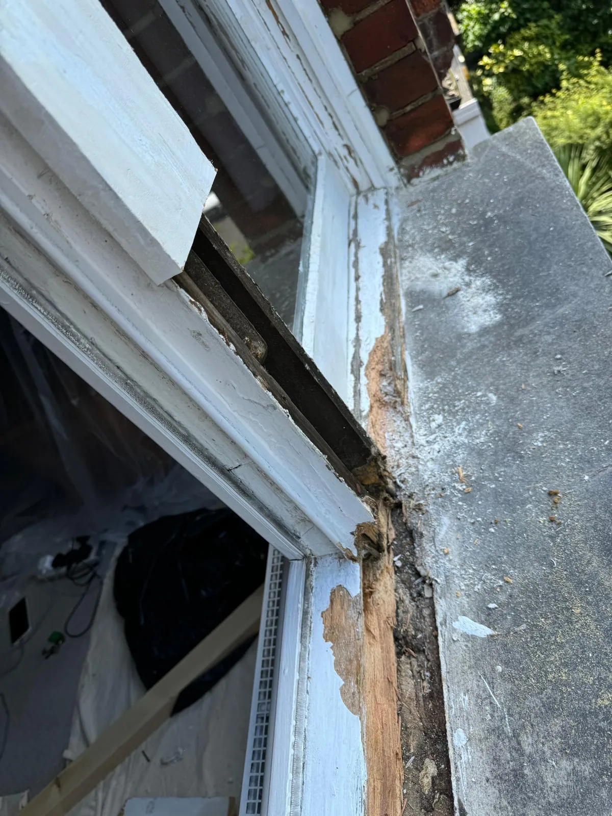 Close-up of rotted sash window sill exposed with bare timber before repair