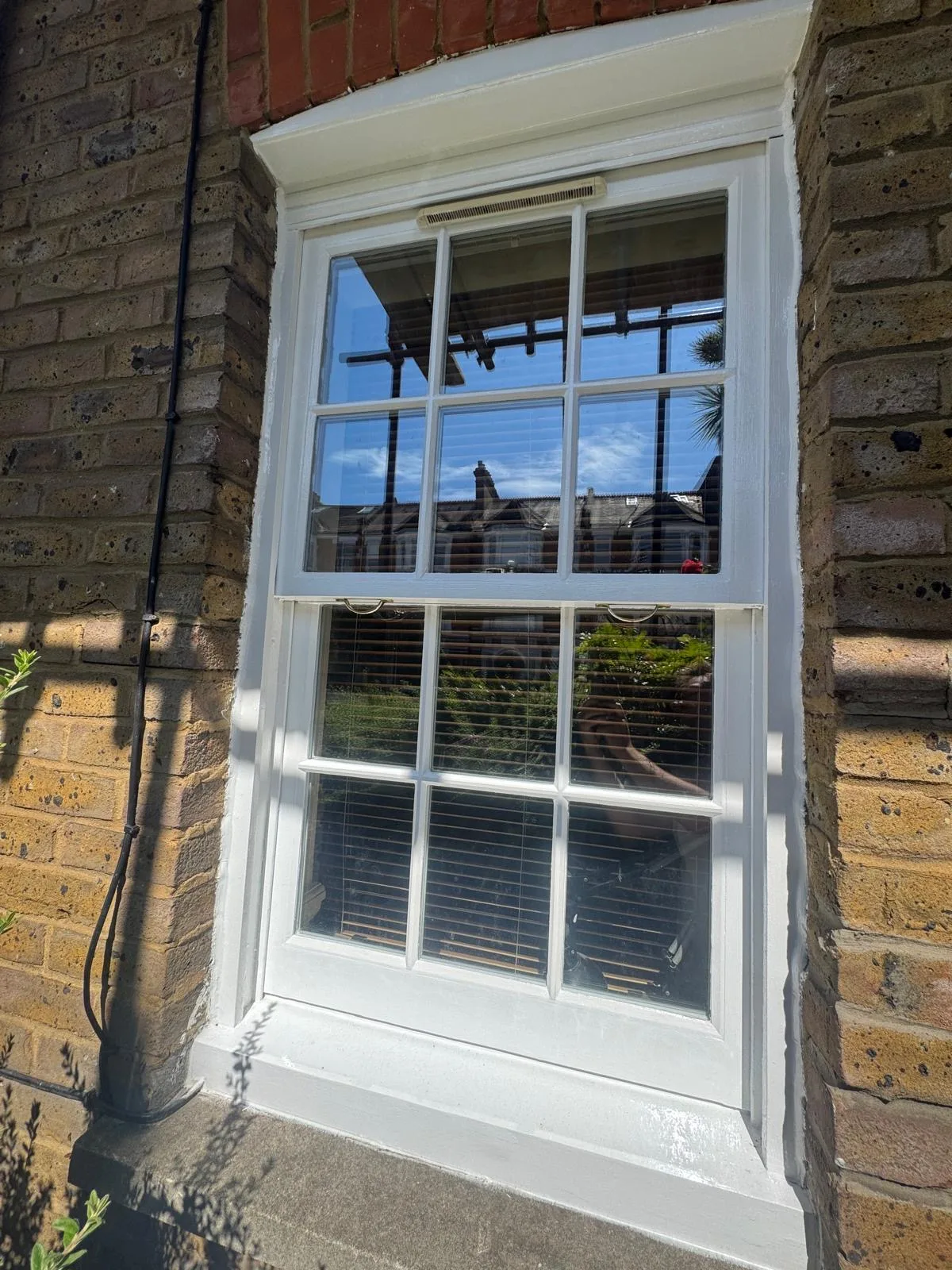 Freshly repainted sash window overlooking London rooftops from a rear elevation