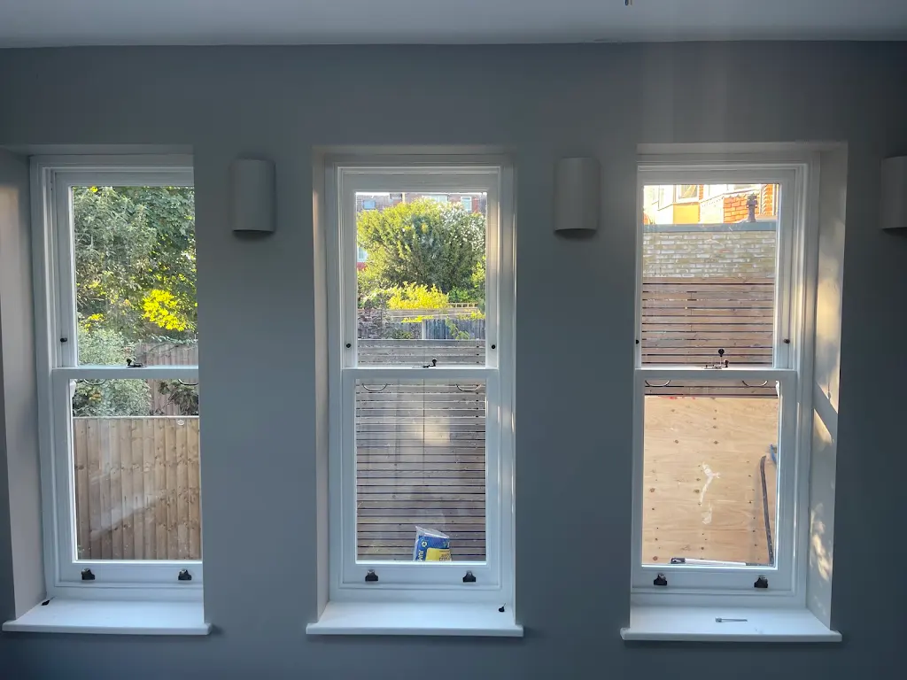 Three restored sash windows with crisp white frames in a grey living room
