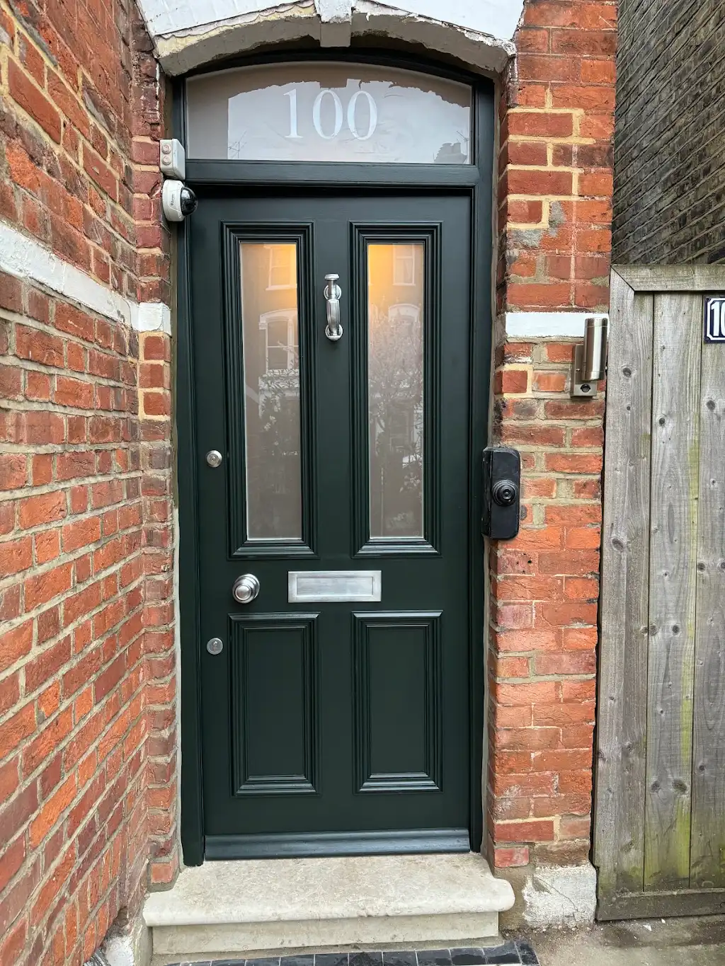 Dark green Victorian front door restored with polished chrome hardware