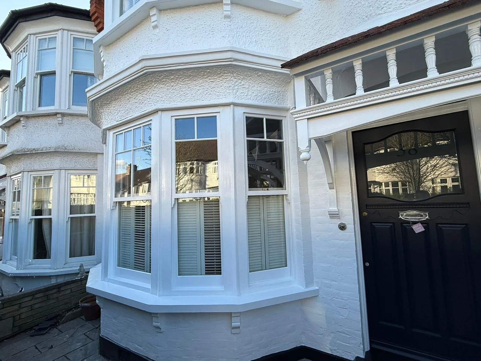 Freshly repainted white bay window and porch on a rendered London home