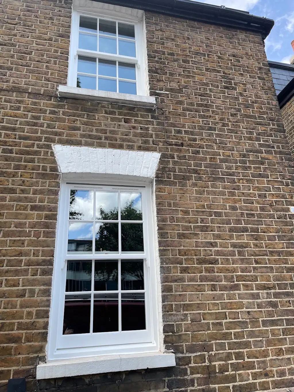 Restored white sash windows on a traditional London brick townhouse