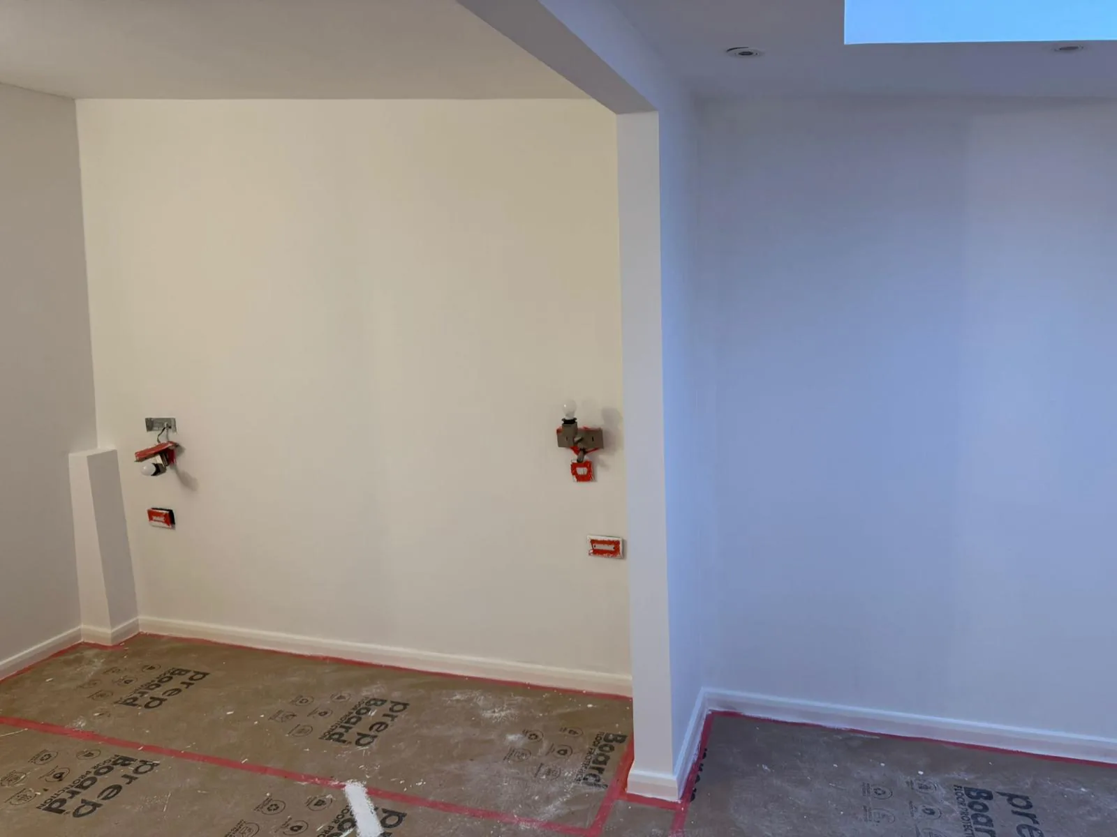 Freshly painted white loft room with recessed alcove mid-decoration over floor protection