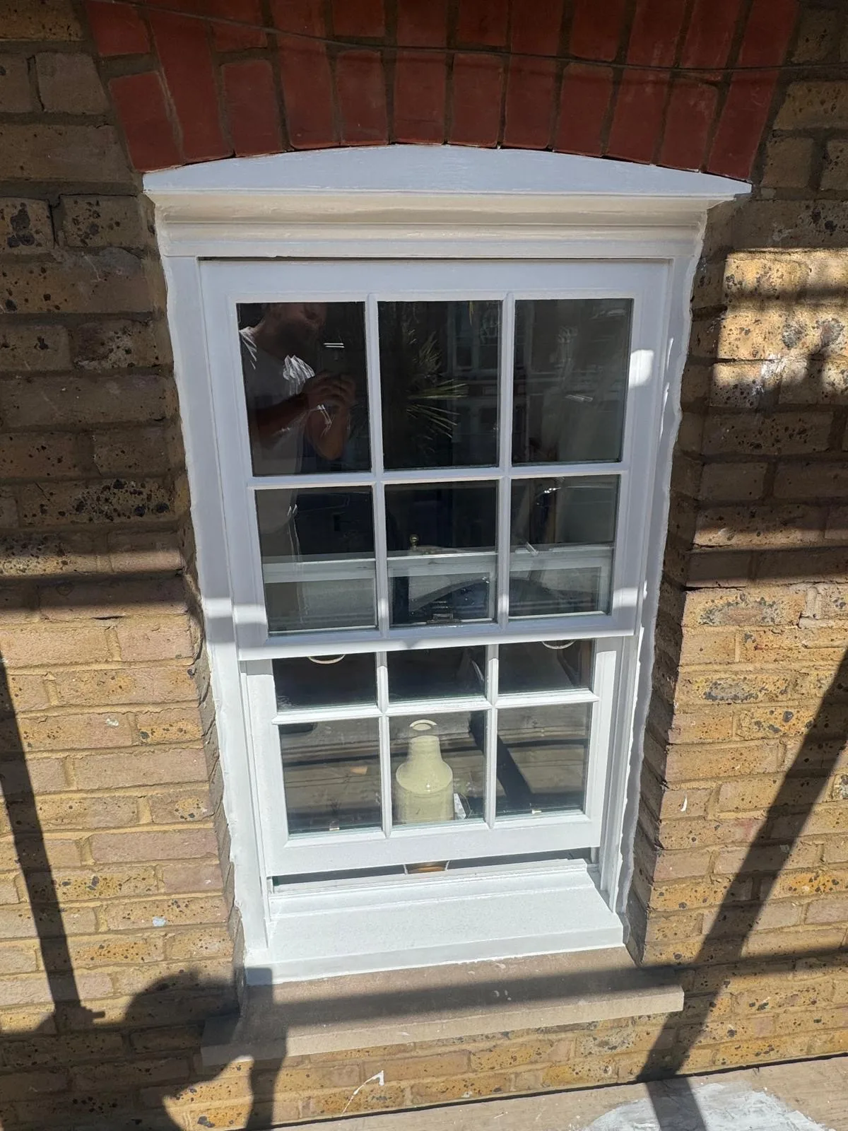 Restored white sash window with fresh gloss on a period London brick home