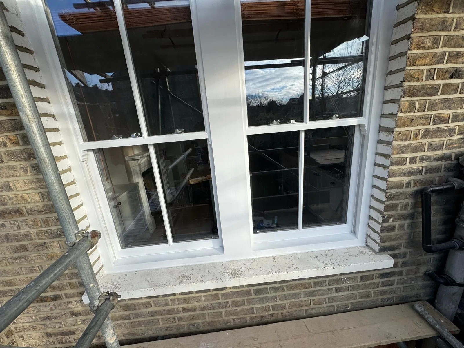 Twin sash windows with fresh white paintwork on a London brick façade