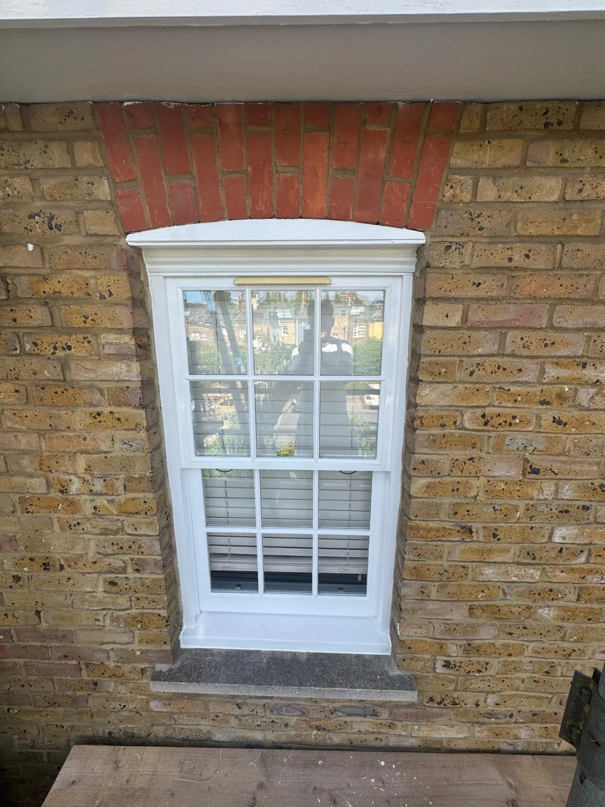 Restored Georgian sash window with brass fittings on a London brick townhouse