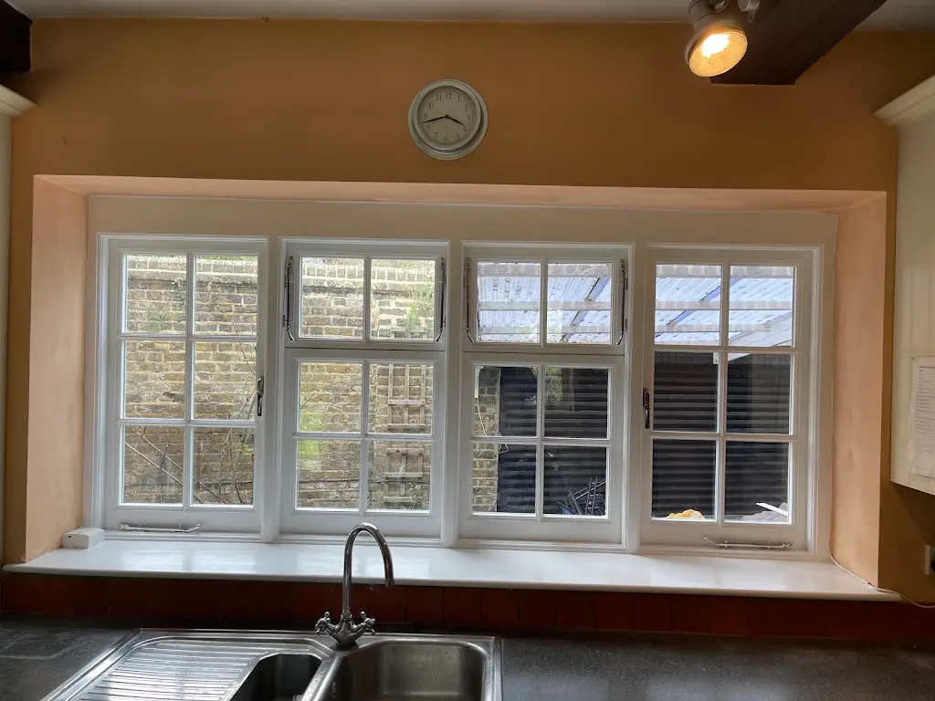Kitchen casement windows repainted white above a sink and prepped walls