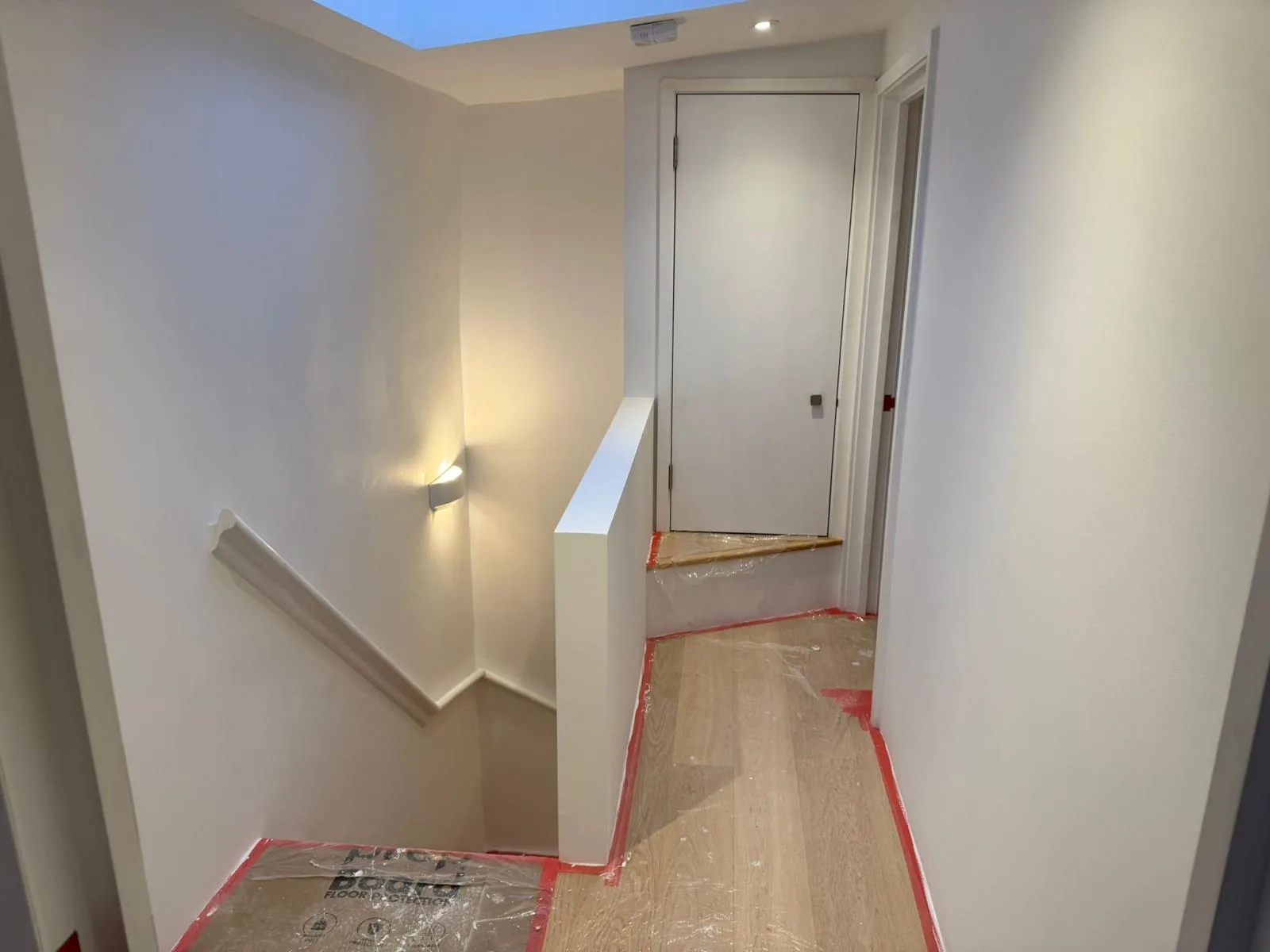 Freshly repainted landing with wall light, skylight and oak flooring after decoration