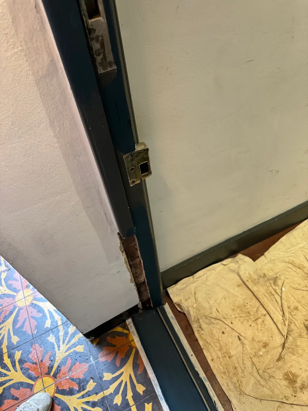 Damaged door frame at floor level showing timber rot before restoration