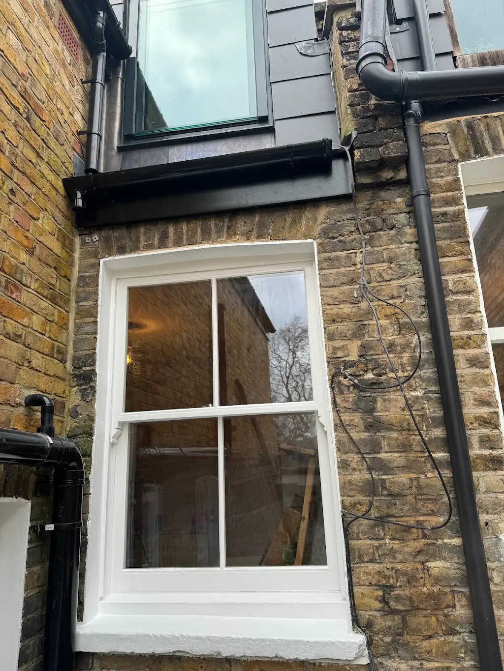 Restored sash window with fresh white frame on a London brick rear elevation