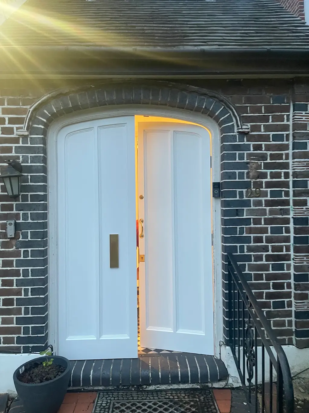 Restored white front door with gloss finish on a Tudor-style home