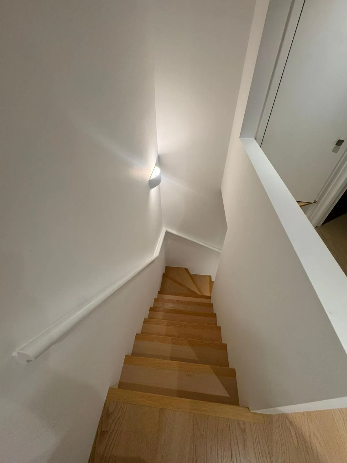 Repainted staircase in warm white with restored oak treads and slim handrail