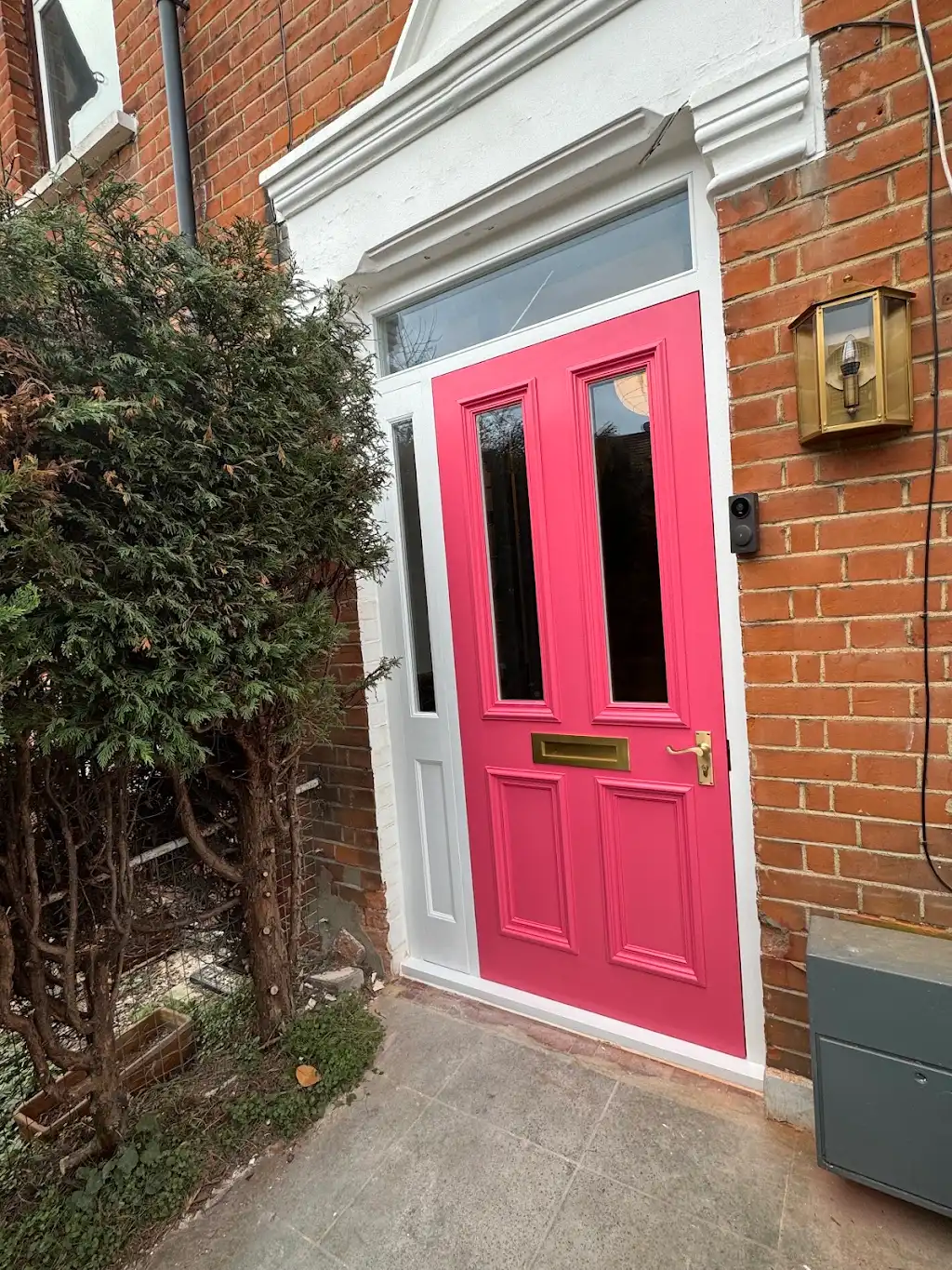 Bold pink front door repainted with brass hardware on a Victorian home