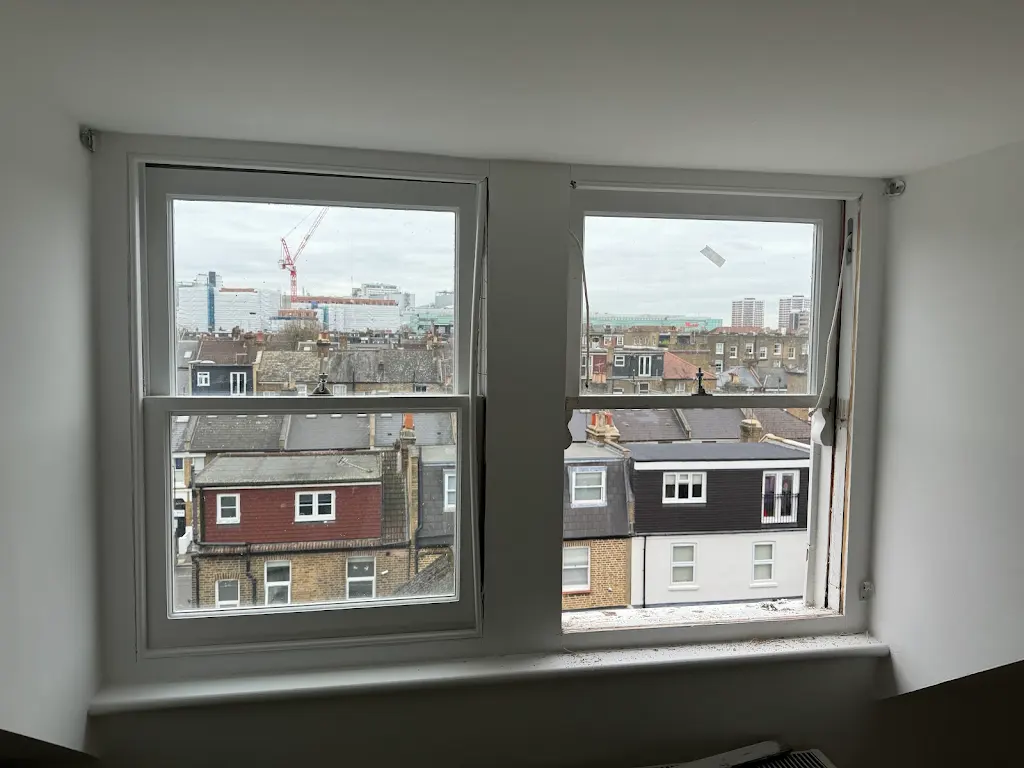 Restored double sash windows in a loft bedroom with London skyline view