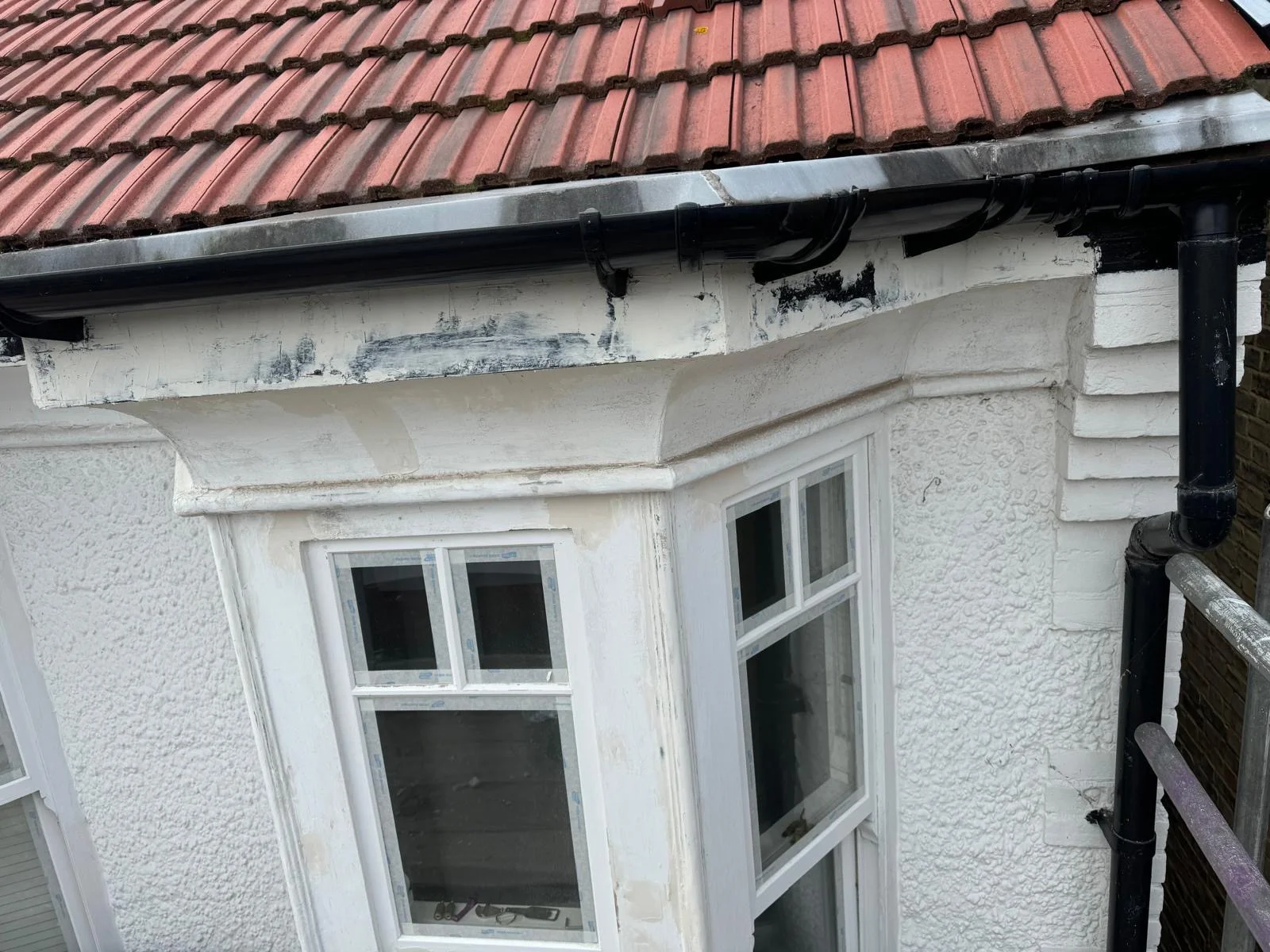 Bay window fascia with black peeling paint stripped back to bare timber mid-preparation