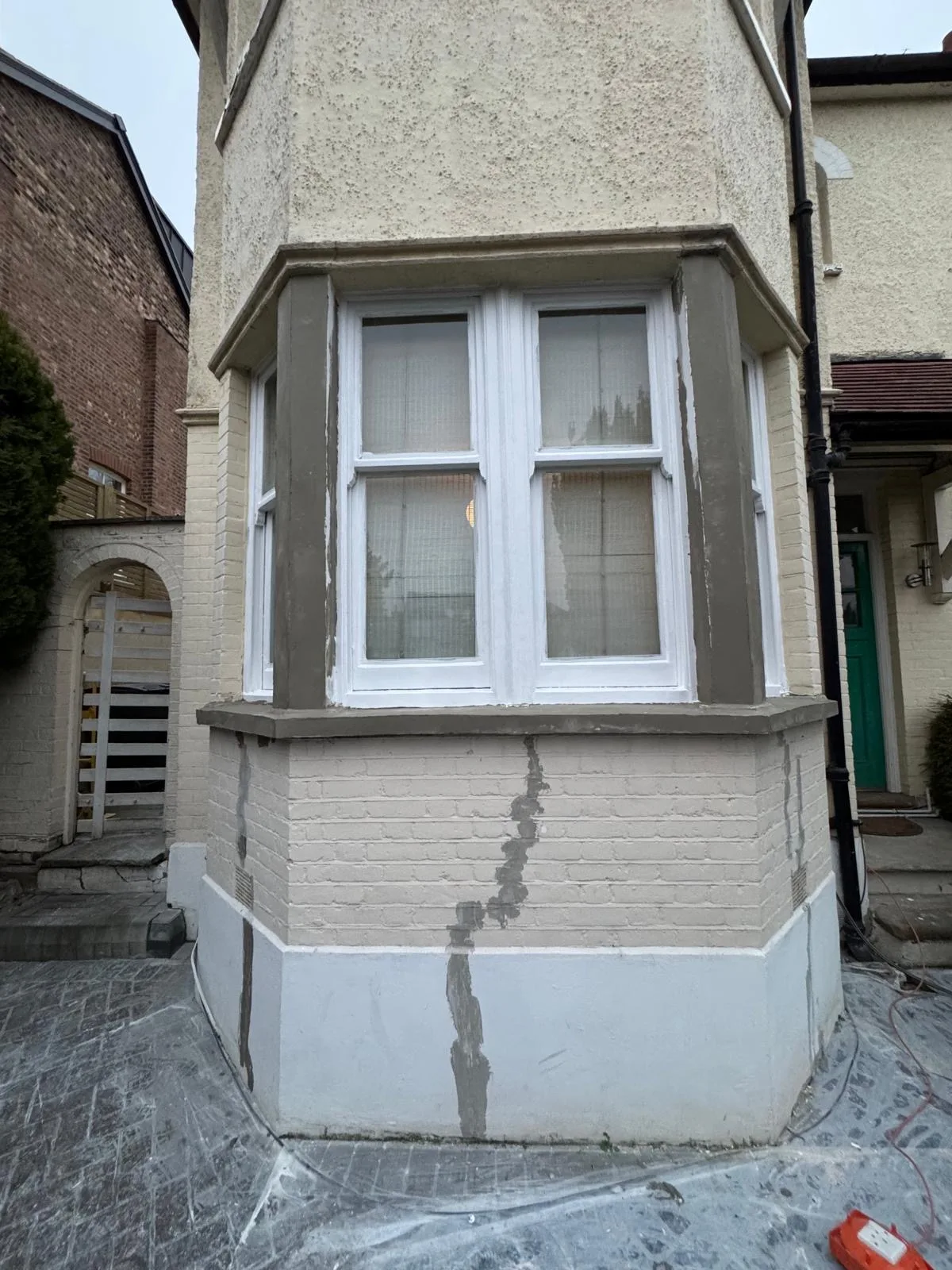 Bay window mid-restoration with primed frames and repaired render