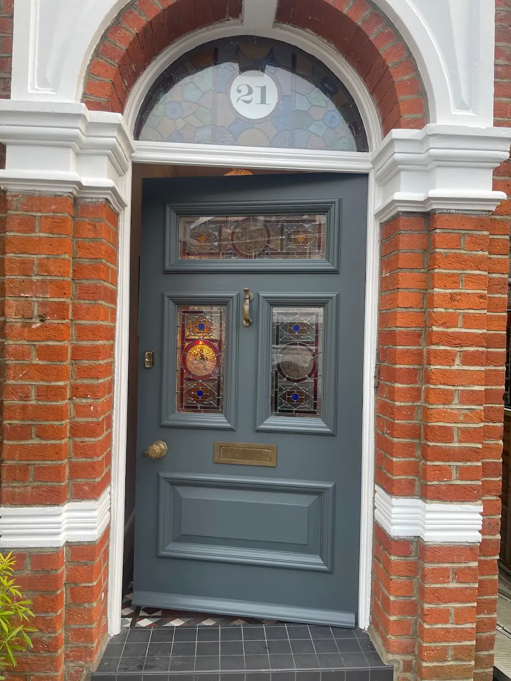 Deep grey Victorian front door with restored stained glass panels