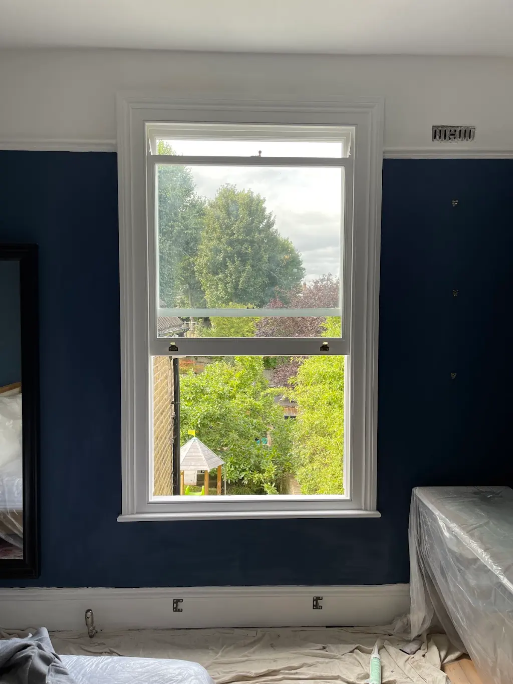 Restored sash window in a deep navy bedroom mid-decoration