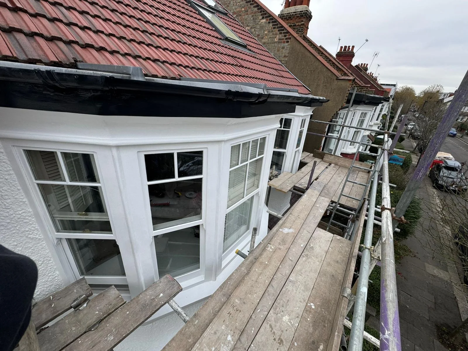 Freshly repainted white sash bay windows viewed from scaffold on a London terrace