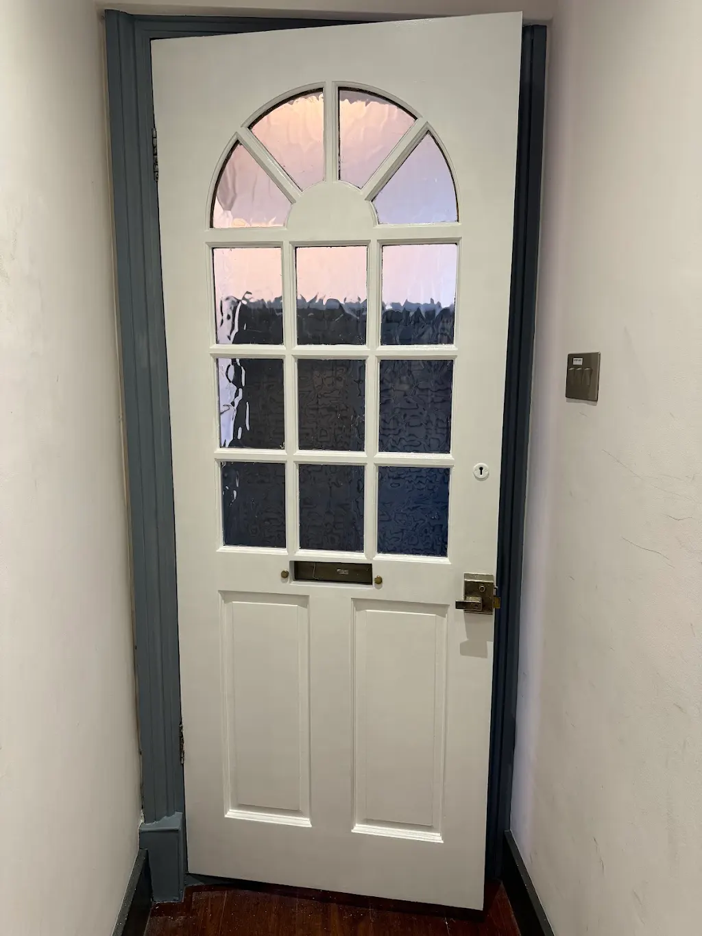 Interior view of restored arched front door repainted in soft white