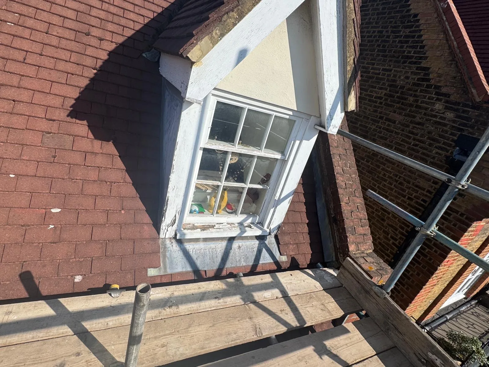 Loft sash window with peeling paint prepped for restoration from scaffold