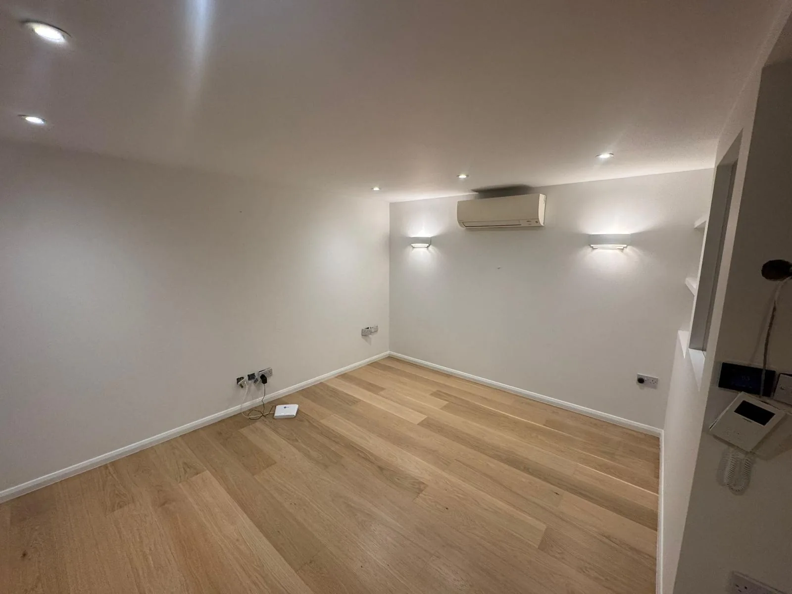 Finished loft living room with soft white walls, wall lights and oak flooring
