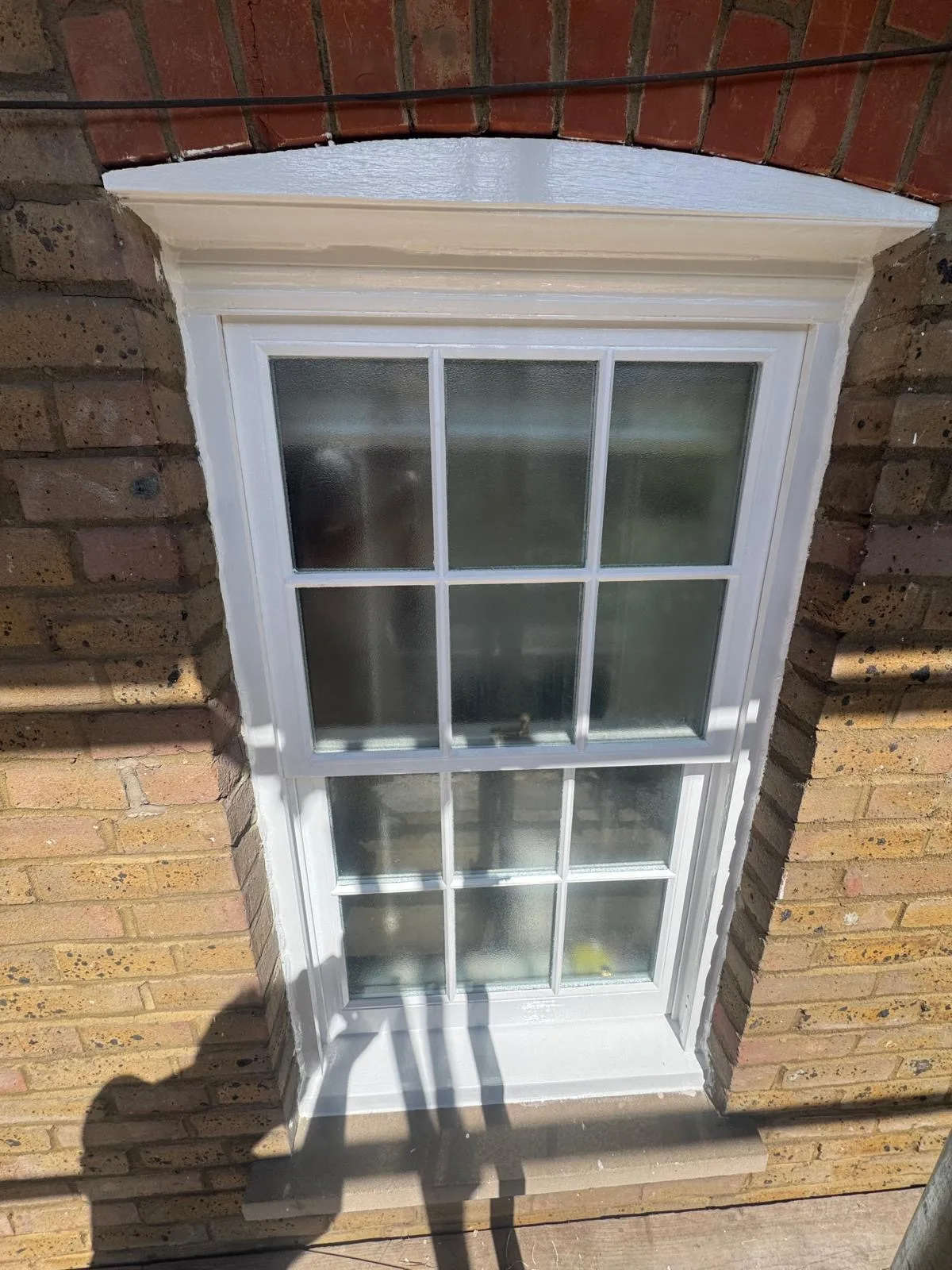Restored sash window with obscured privacy glass on a London brick façade