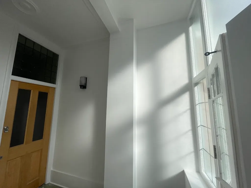 Freshly painted white hallway with natural light and oak door