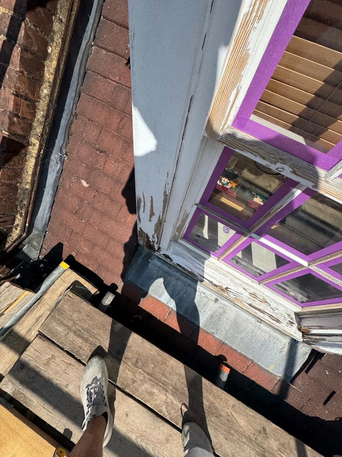 Sash window frame with peeling paint viewed from scaffold before restoration