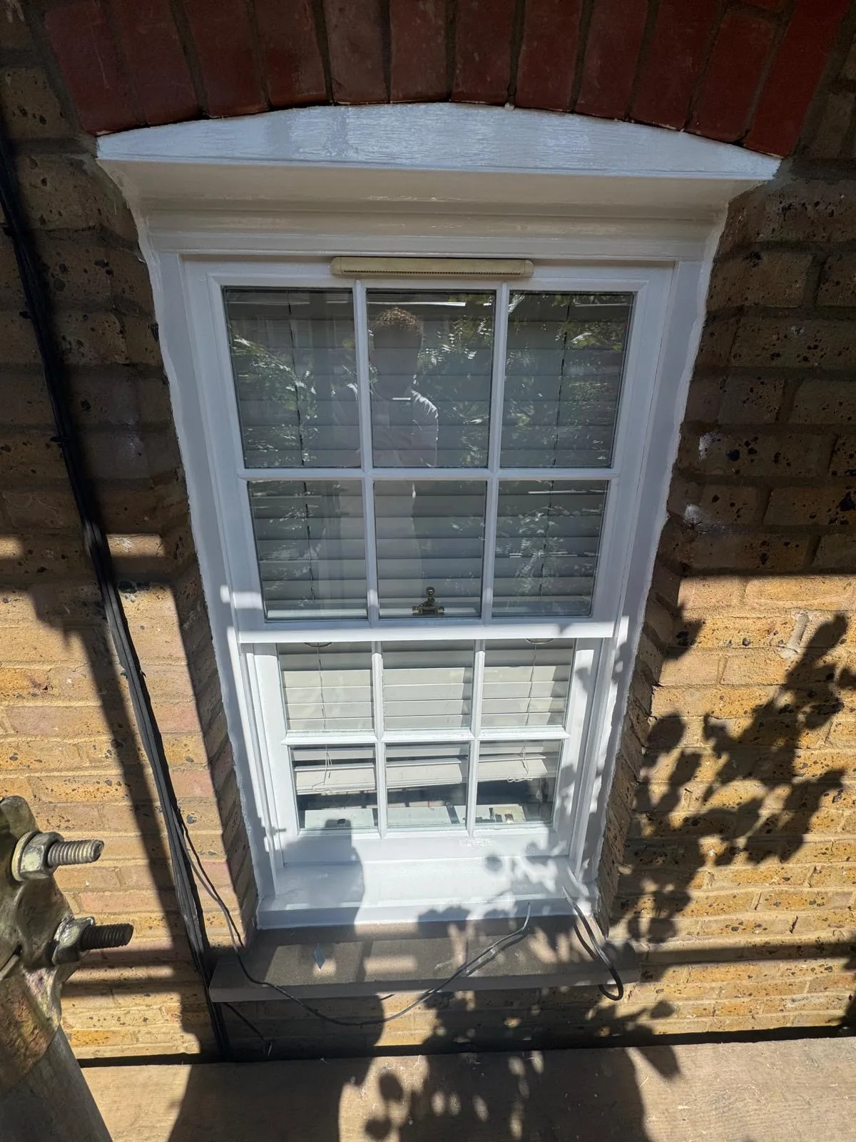 Restored sash window with brass hardware viewed from below on a London façade