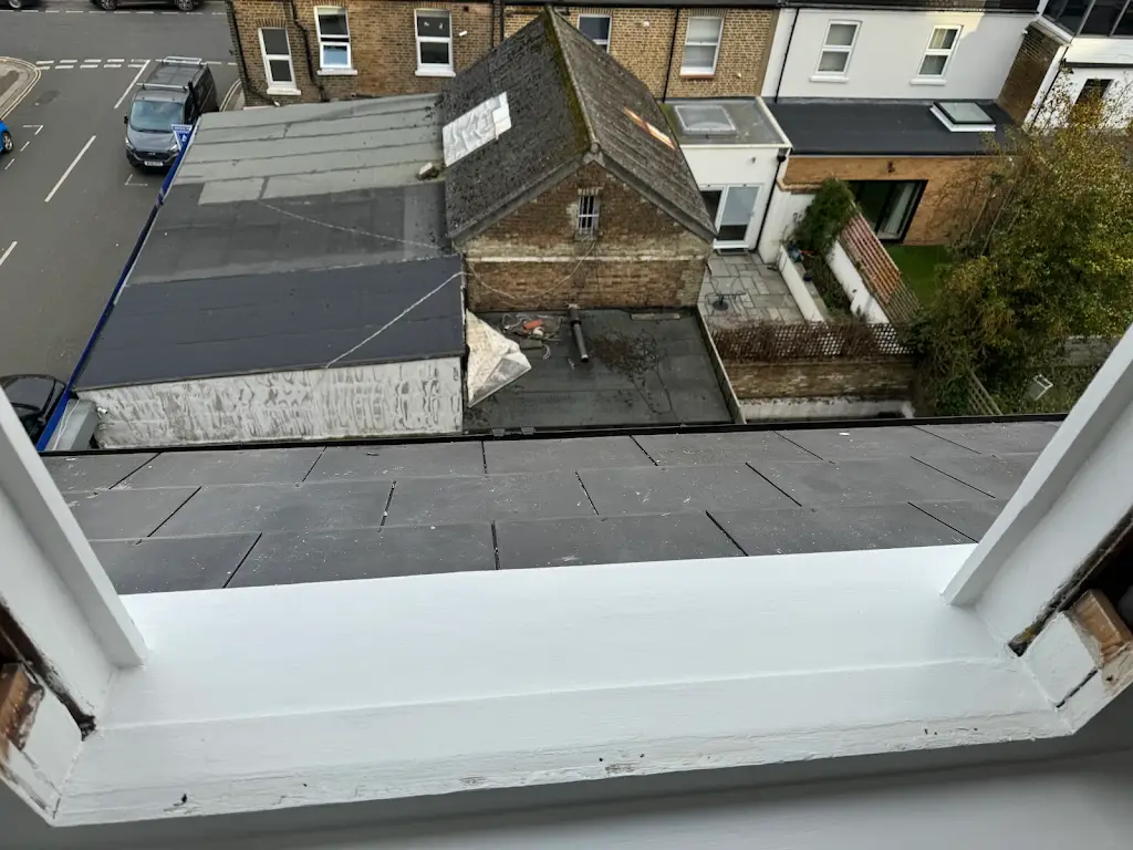 Loft dormer window sill repainted in bright white over slate roof