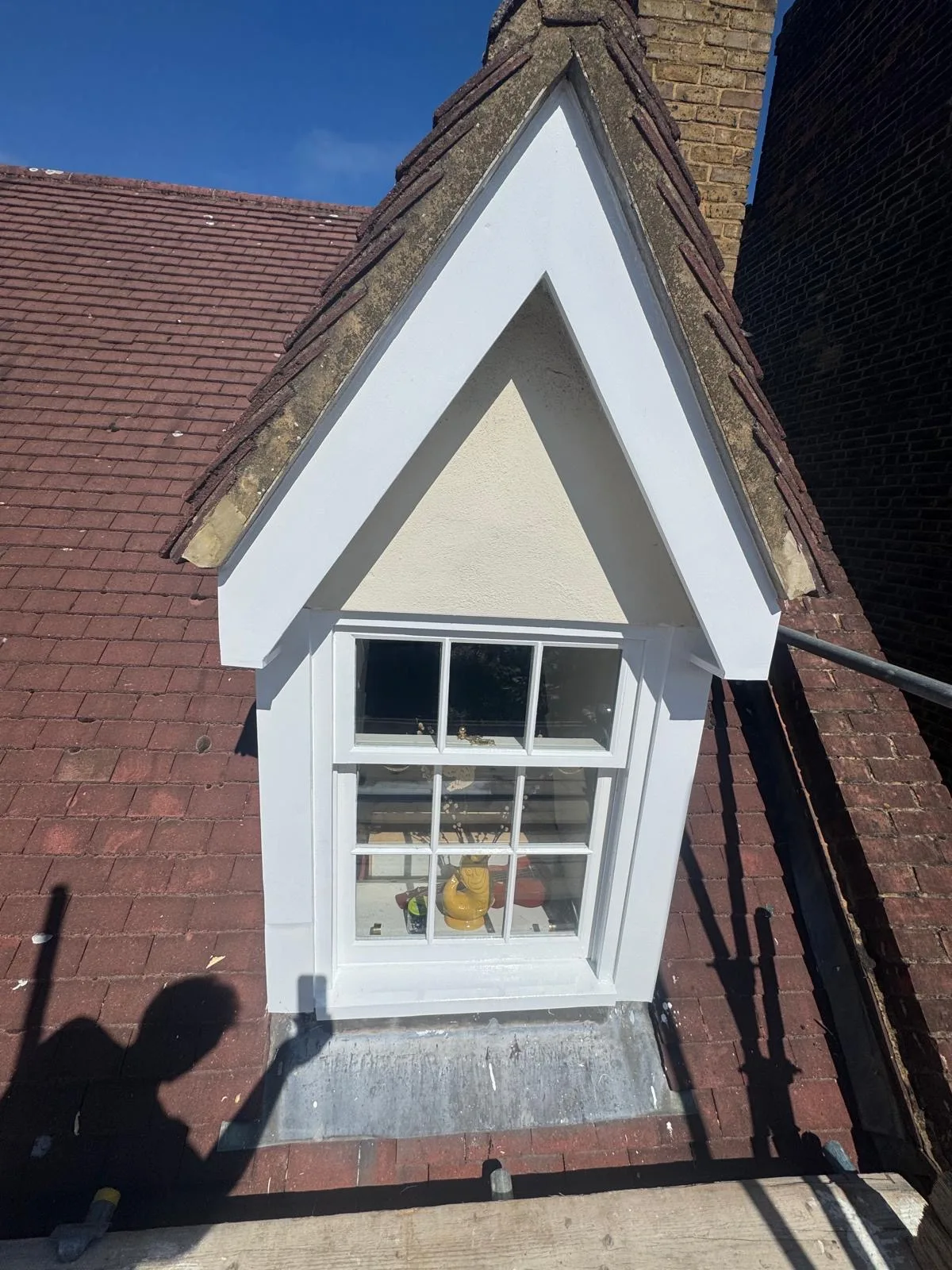 Restored white gabled dormer sash window on a red tiled London roof