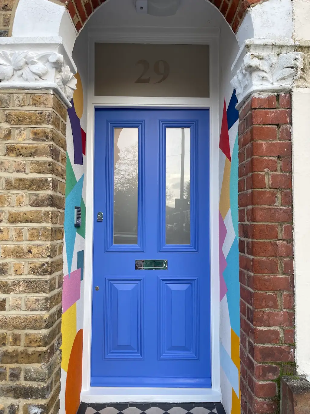 Vibrant blue front door with geometric mural on a Victorian entrance
