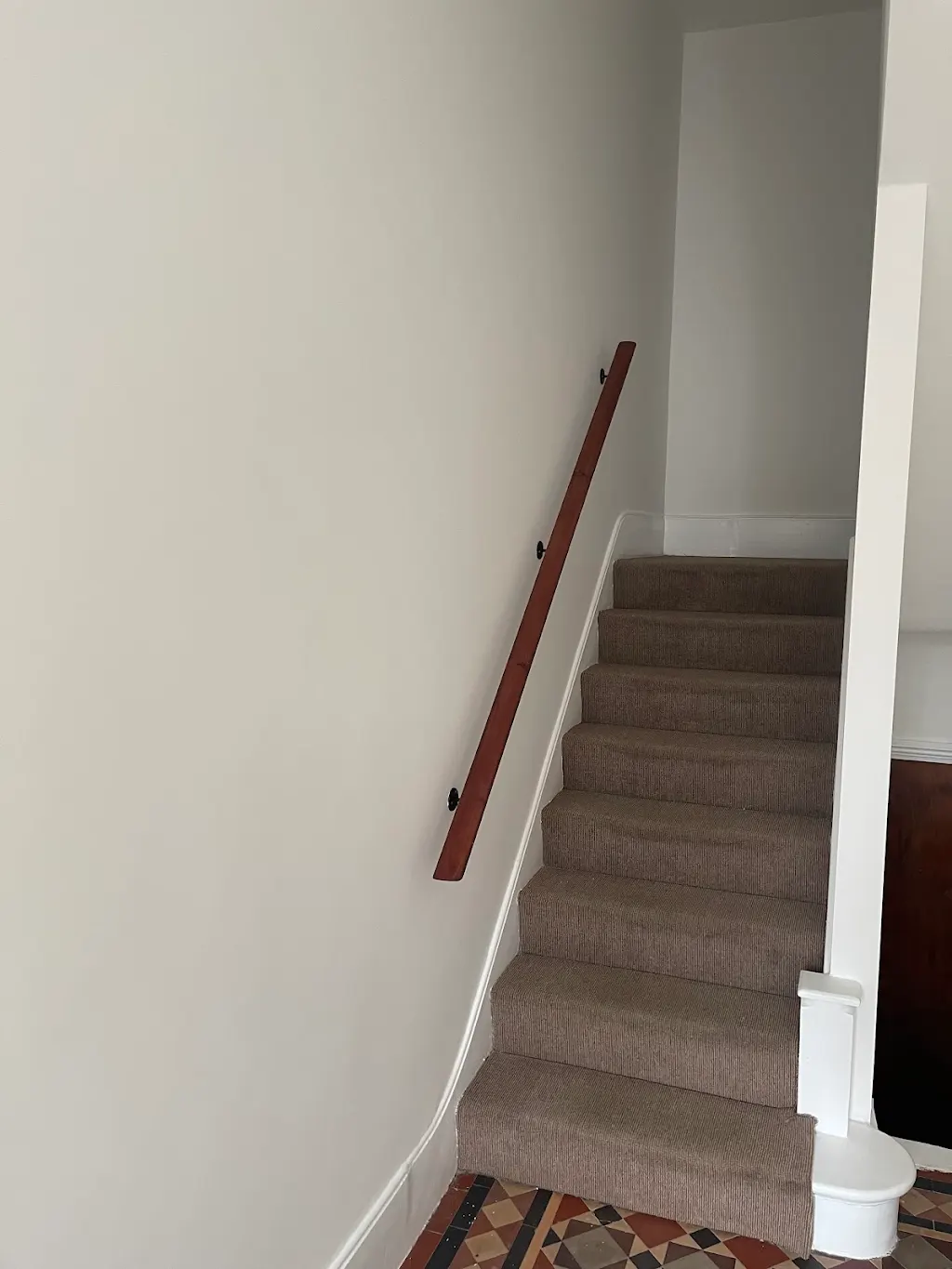 Repainted staircase with restored mahogany handrail over Victorian tiles