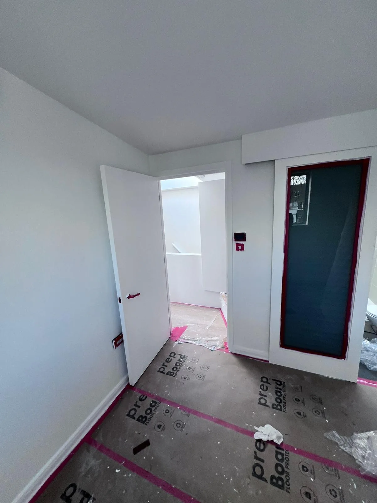 Newly painted bedroom with white internal door and obscured glass panel mid-decoration