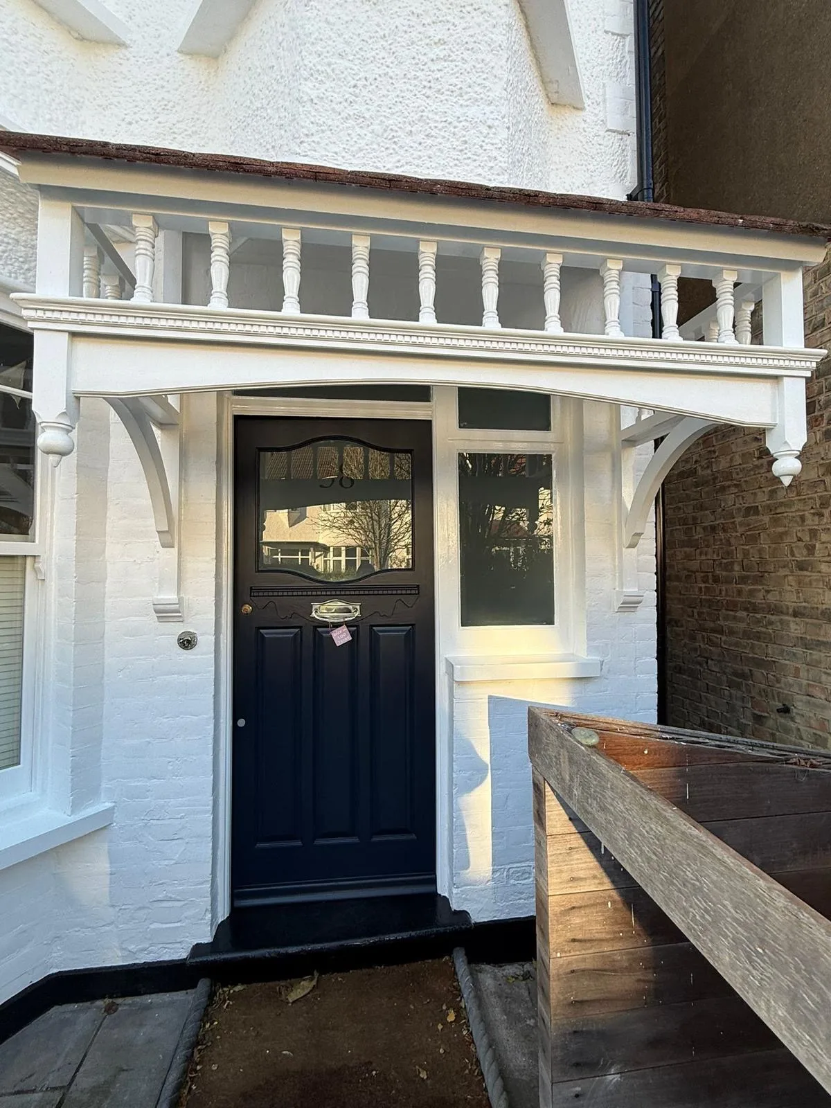 Navy blue Victorian front door restored beneath a repainted white porch canopy
