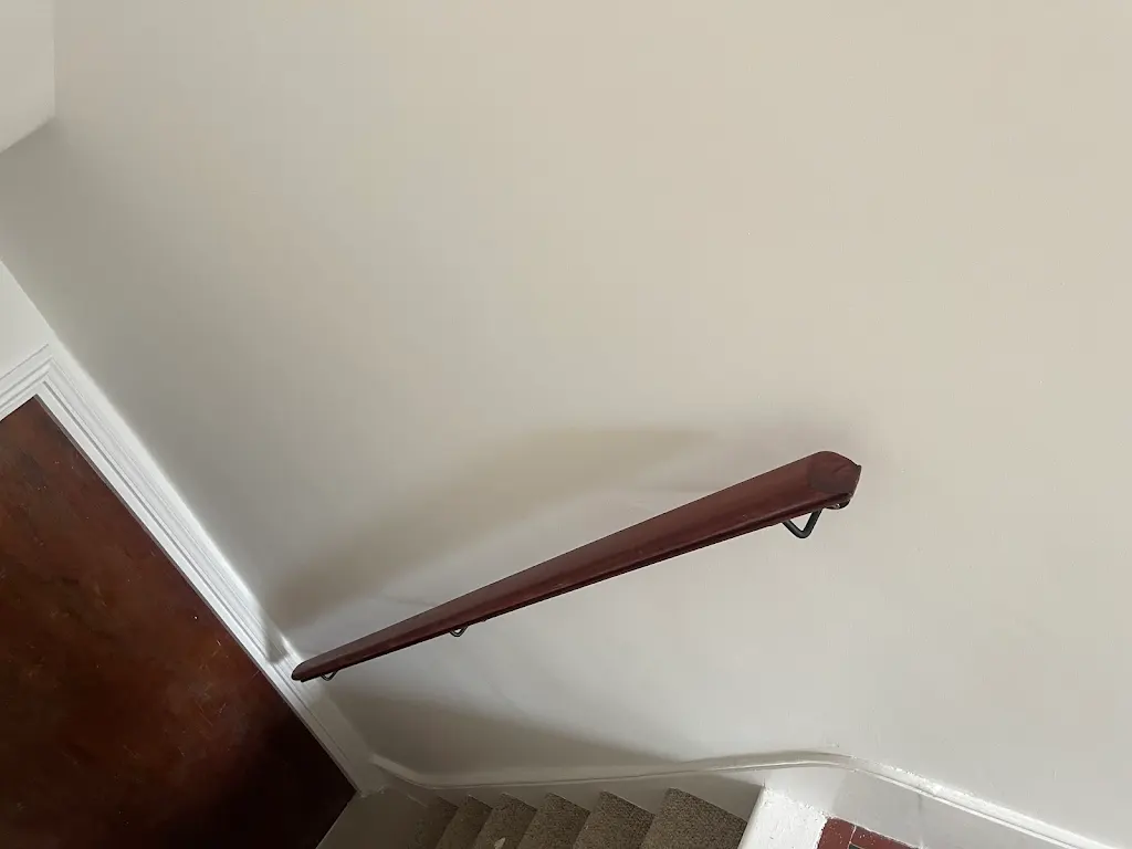 Detail of restored mahogany handrail against a freshly painted wall