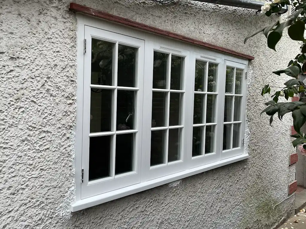 Exterior white timber casement windows on a pebbledash cottage
