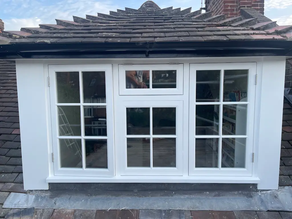 Restored white timber dormer casement windows on a tiled roof