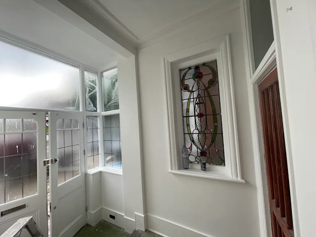 Restored period hallway with white walls and stained glass feature window