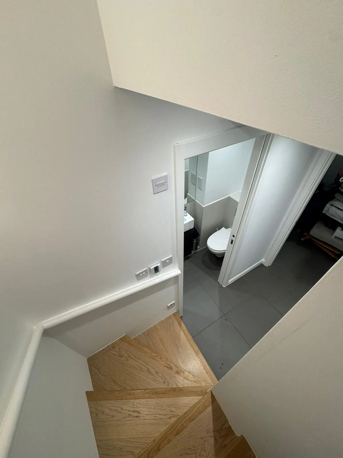 Winder staircase repainted white leading down to a tiled cloakroom