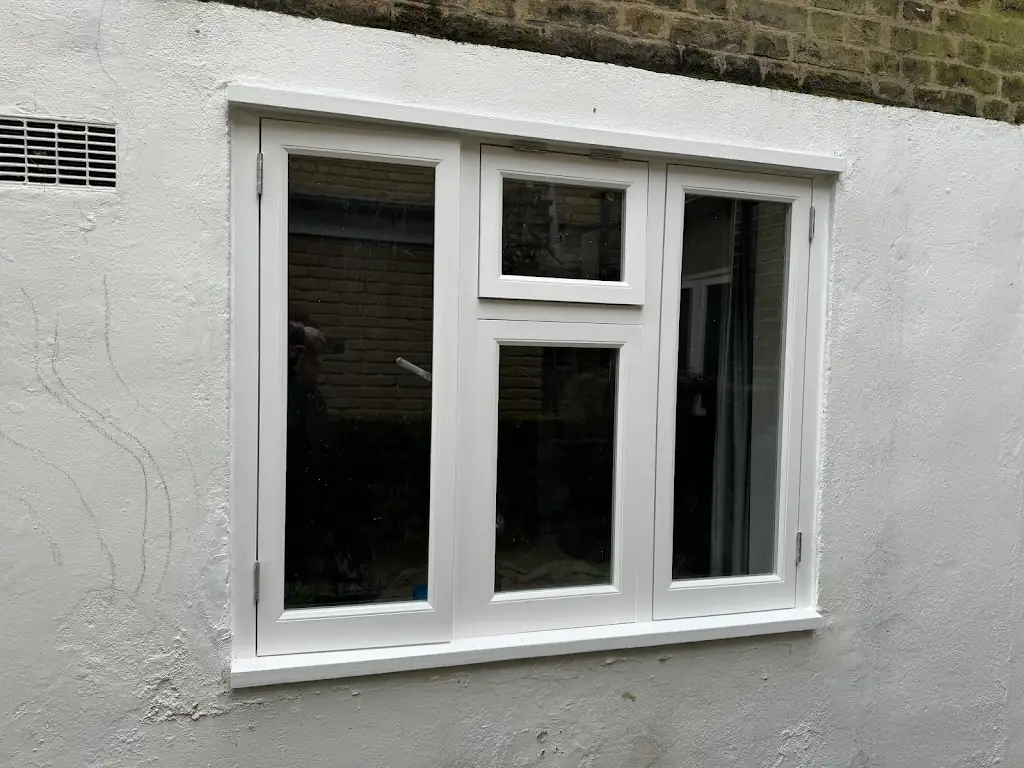 Freshly repainted white timber casement window on a rendered rear elevation