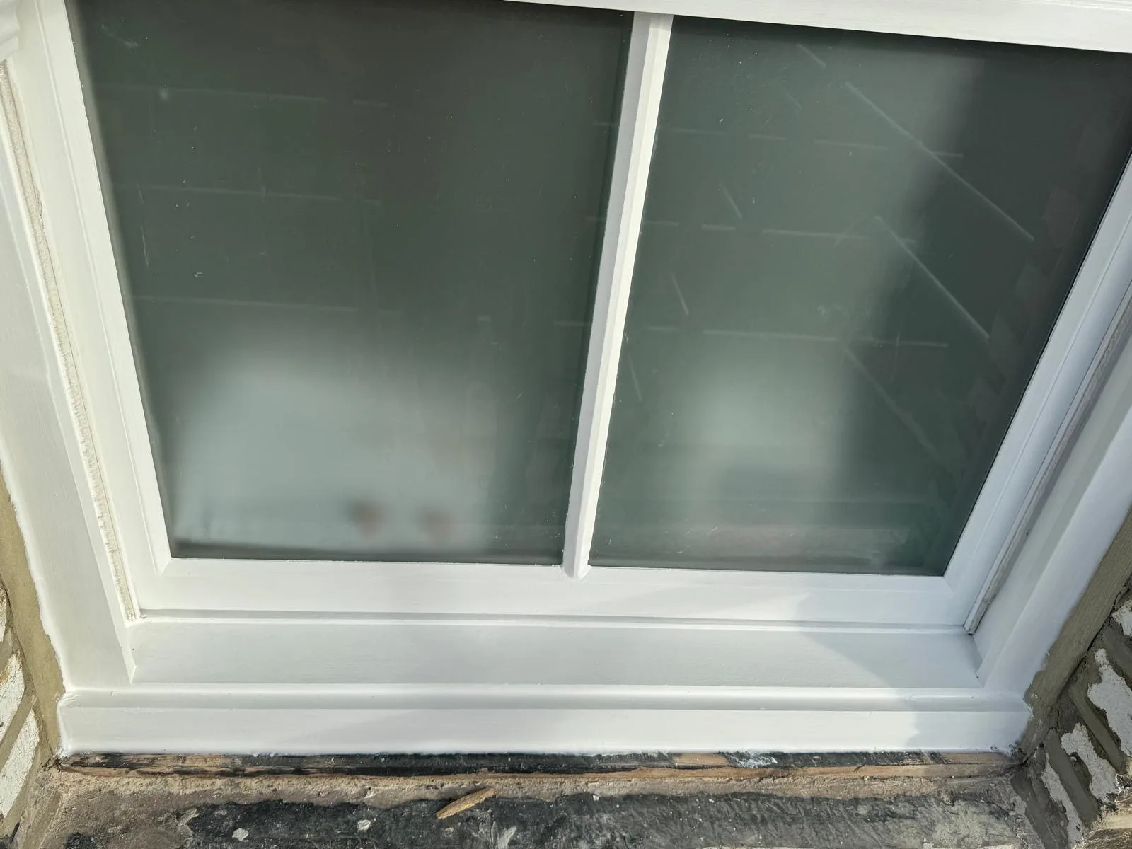 Close-up of freshly repainted sash window over rotted sill awaiting timber repair