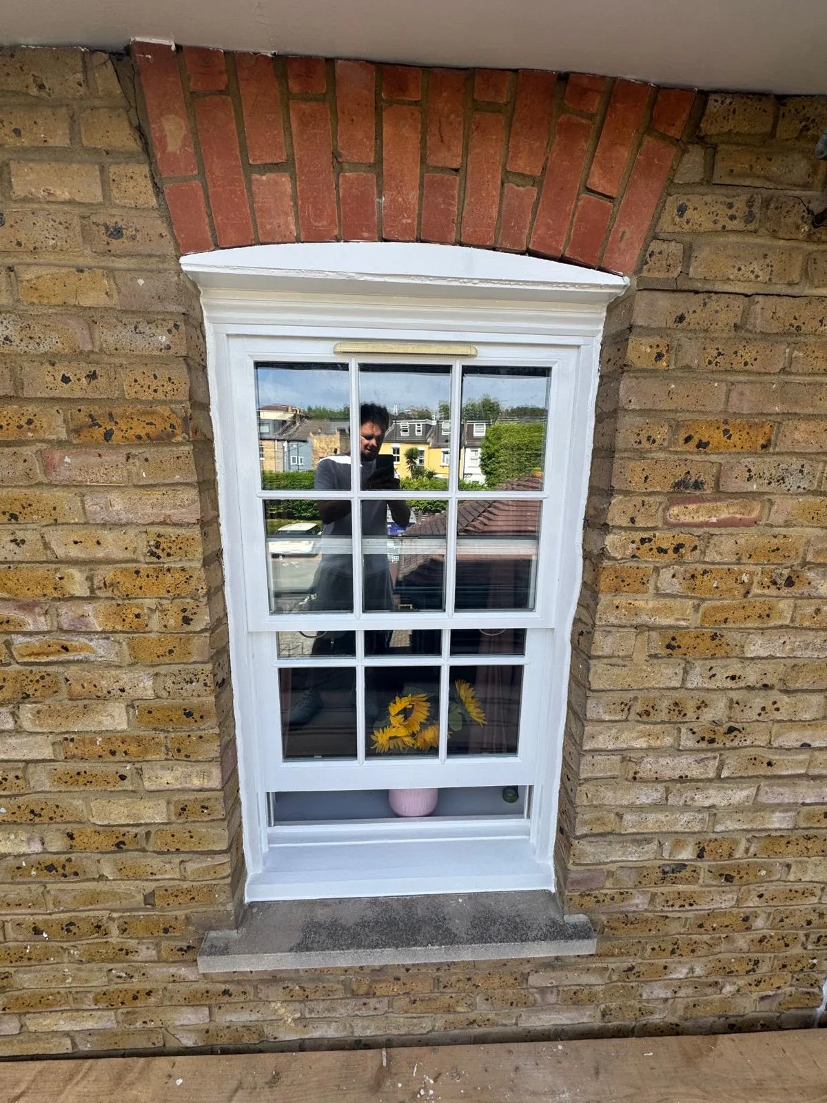 Restored sash window with brass sash lift on a yellow London brick façade