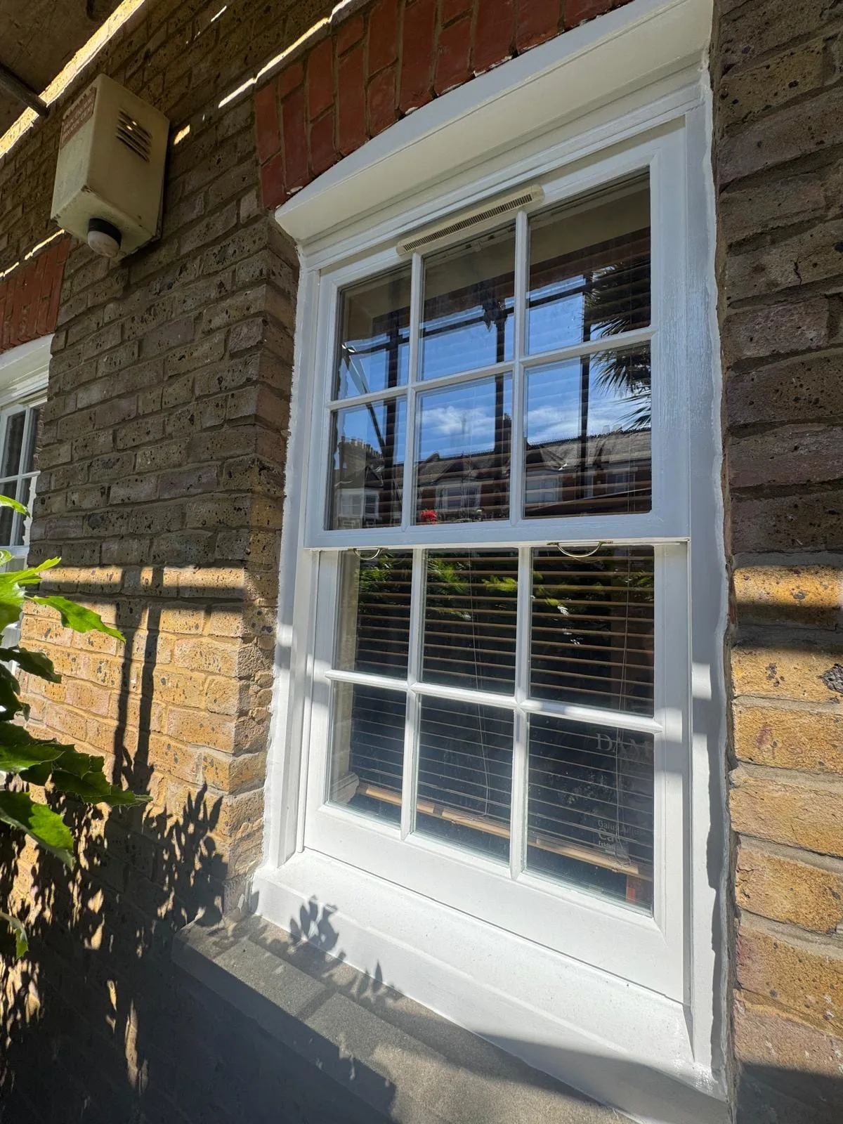 Restored sash window with brass sash lift and vent on a period London façade