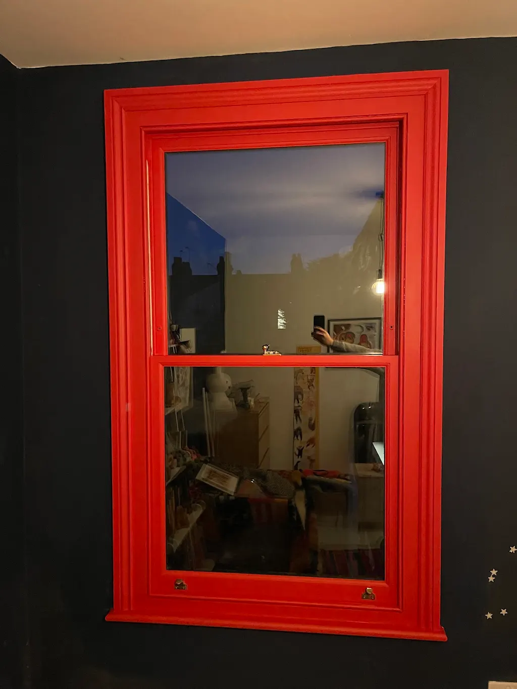 Bold red sash window frame against a deep navy bedroom wall