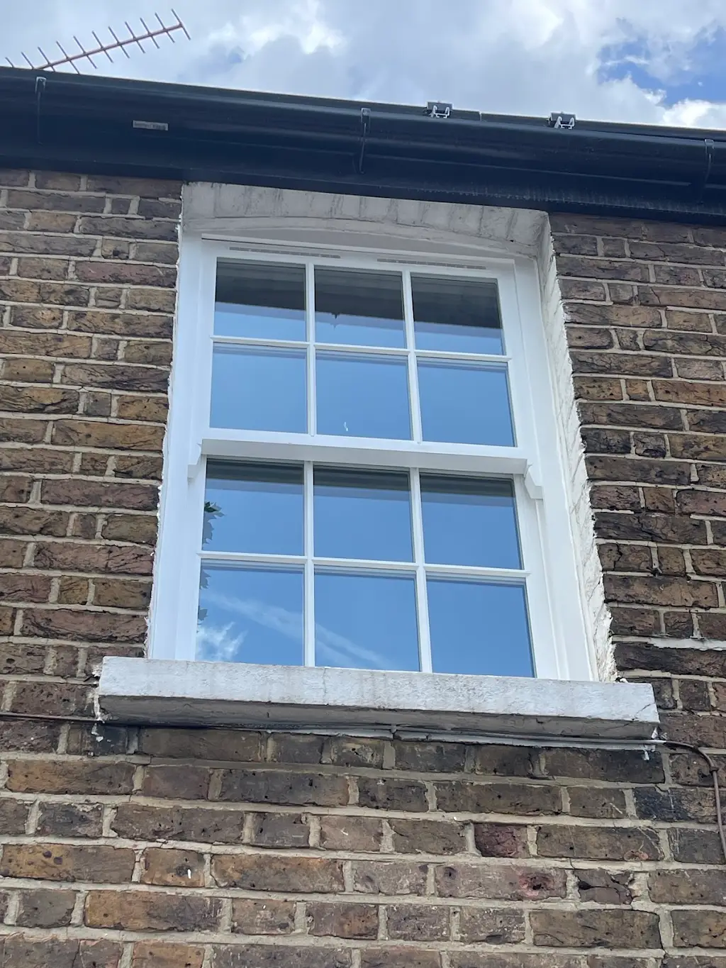 Freshly repainted Georgian sash window on a London brick façade